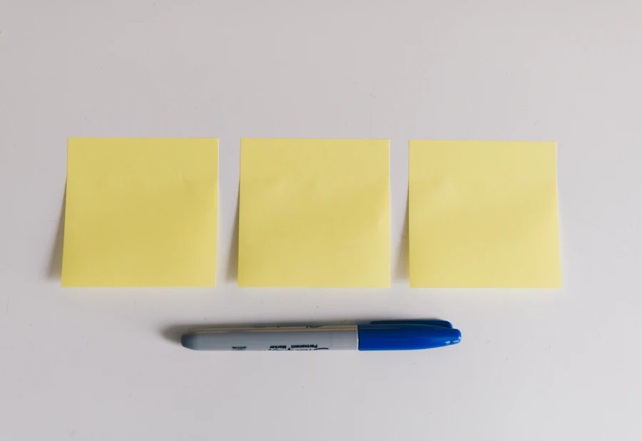 A marker resting beside yellow sticky notes